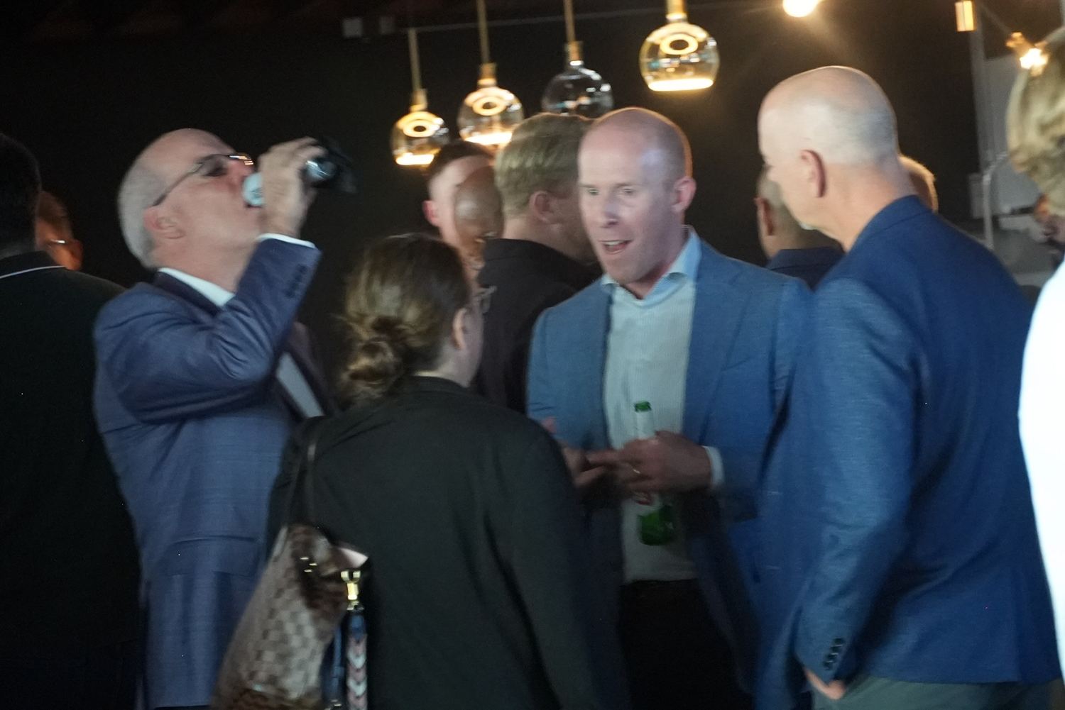 A crowd under the pendant lights at the bar